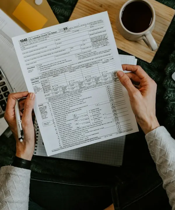 Tax forms being completed with a calculator and laptop