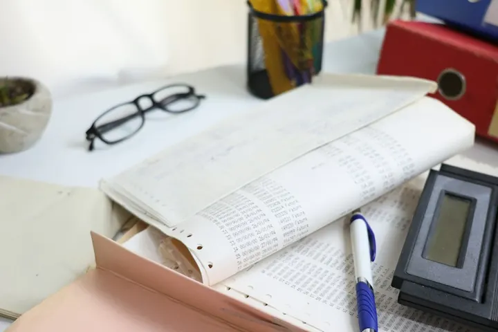 Desk with ledgers, glasses and a calculator