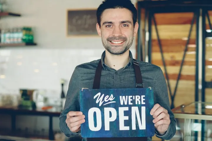 New café owner holding an open sign